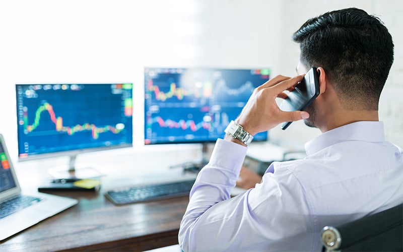 Futures trader managing multiple monitors while on a call