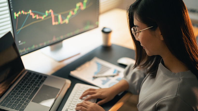 Focused trader monitoring financial market charts on a computer screen.