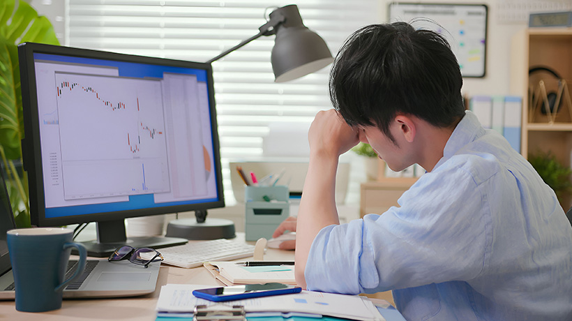 Stressed trader leaning his head on his hand at desk