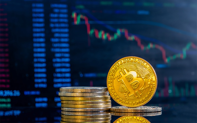 Bitcoin tokens stacked against a volatile crypto market chart