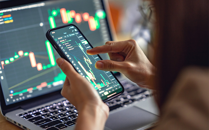 Trader monitoring volatile stock market charts on a smartphone.