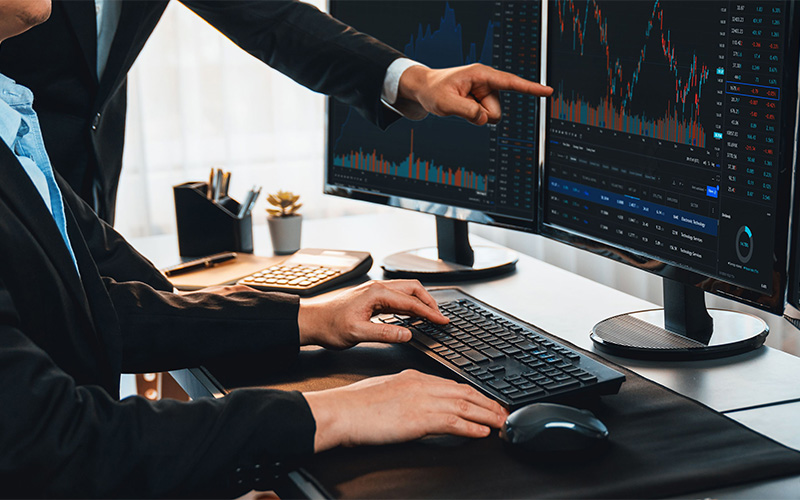 WeMasterTrade mentors discussing technical analysis on professional trading monitors.